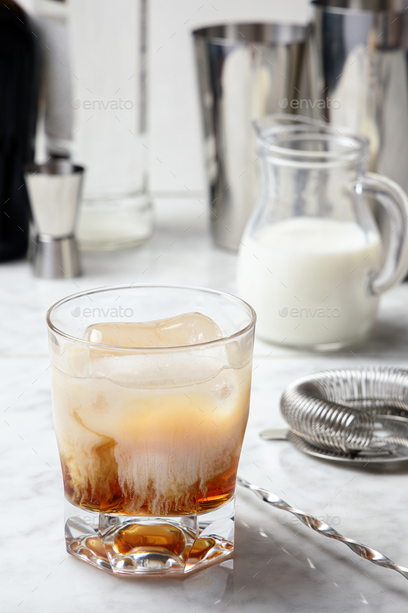 White Russian cocktail preparation. Cream mixing with vodka and coffee liqueur Stock Photo by
